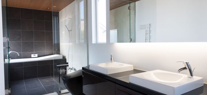 Interior of a modern bathroom, double sink with a big mirror, shower area with bathtub