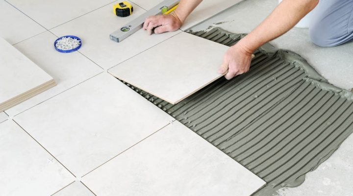 worker laying the ceramic tile on the floor