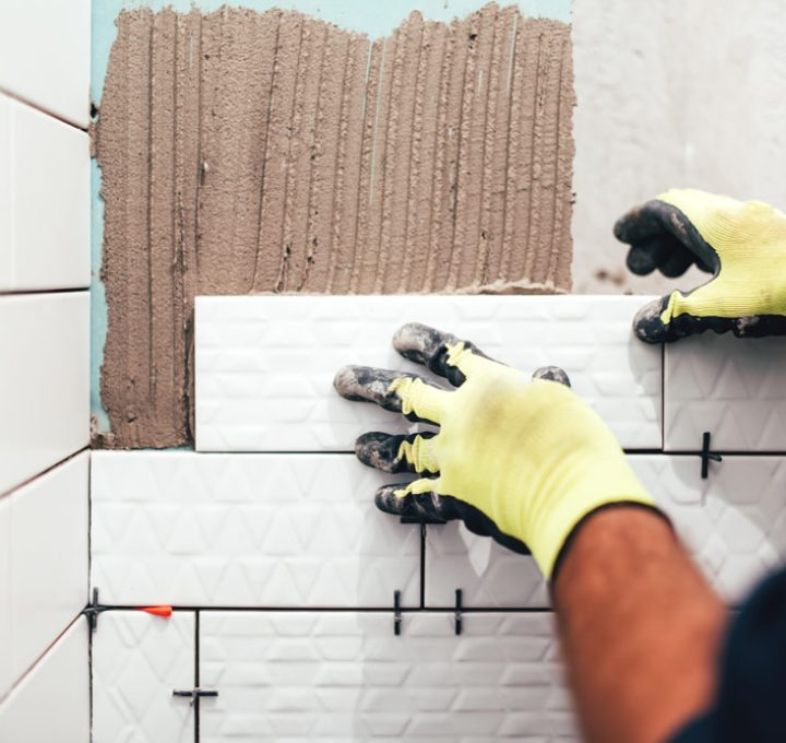 closeup of a hand of a worker installing a porcelain tile on a bathroom